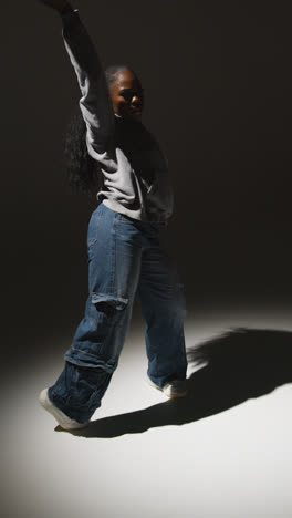 Vertical-Video-Looking-Down-On-Studio-Shot-Of-Young-Woman-Dancing-In-Spotlight-In-Slow-Motion-With-Shadow